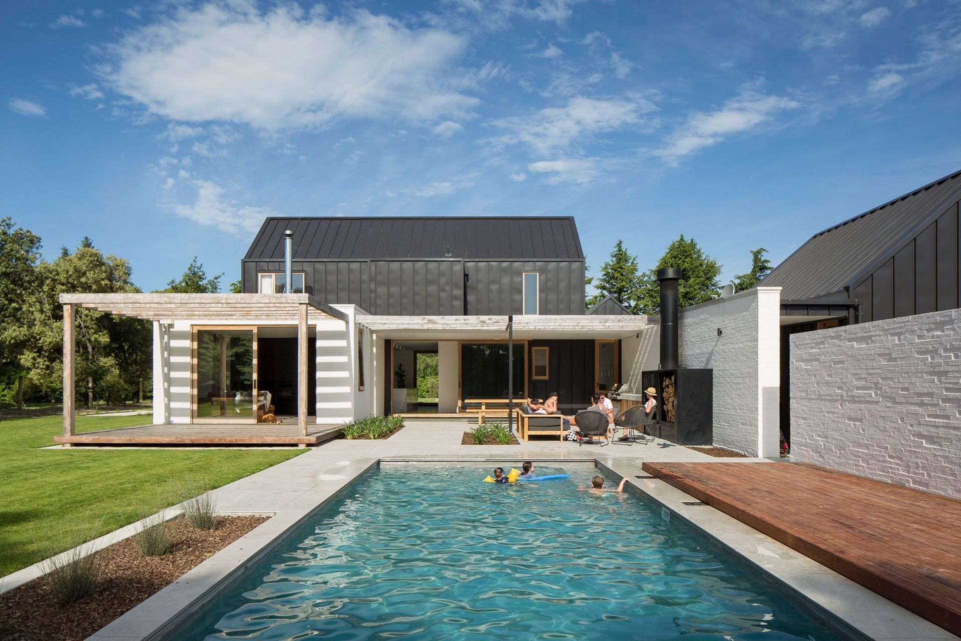 A swimming pool and outdoor entertaining areas are sheltered by a white bagged-brick wall painted in Dulux 'Dannevirke' to match the rest of the house.