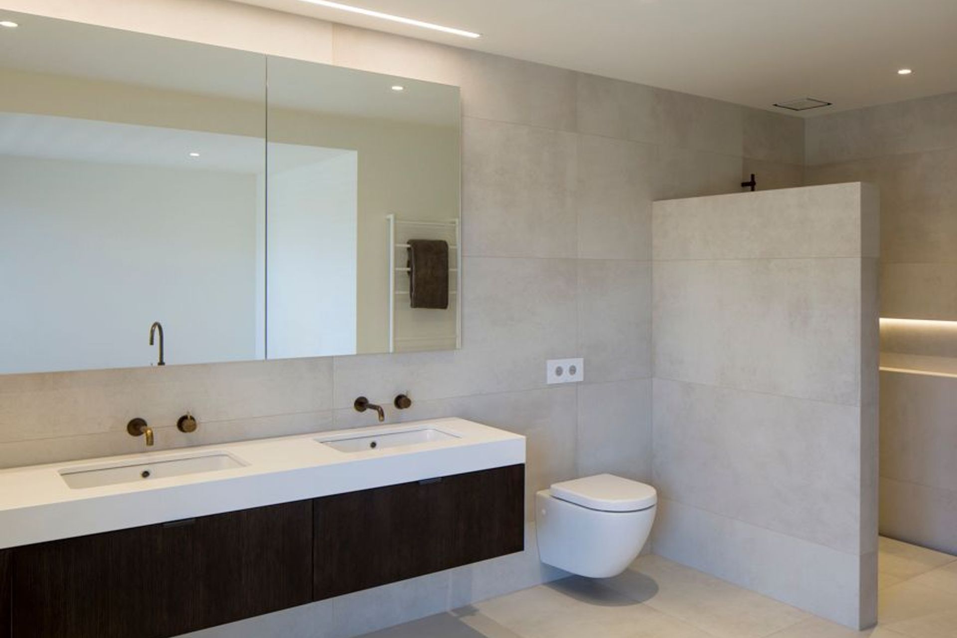 The ensuite bathroom features a custom-built cabinet with dark oak veneer and a stone top. 