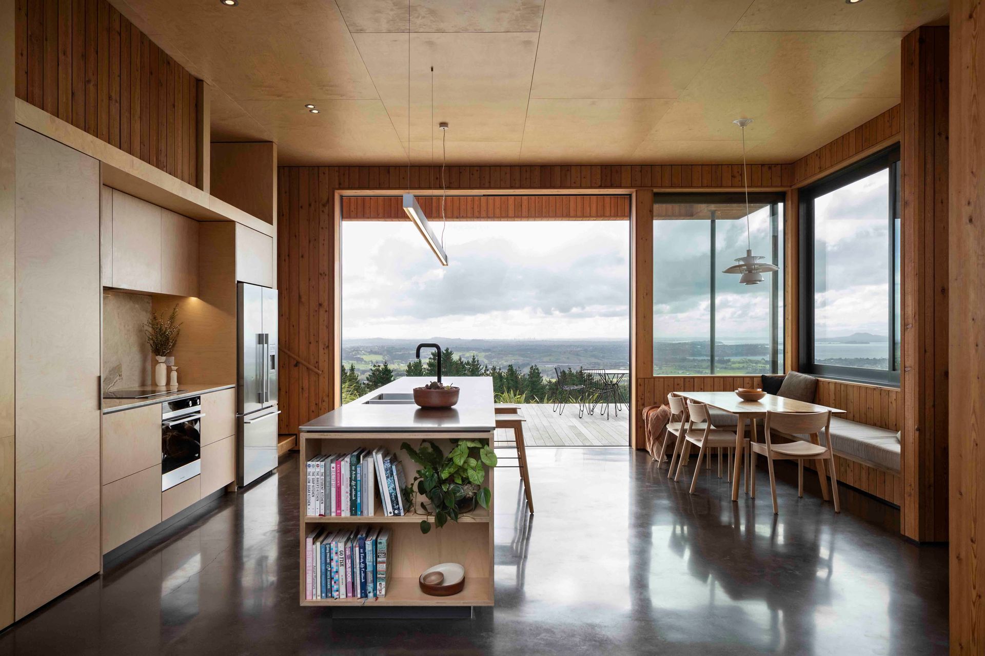 Birch plywood lines the ceiling of the kitchen, creating a biophilic tie to the outdoor spaces.