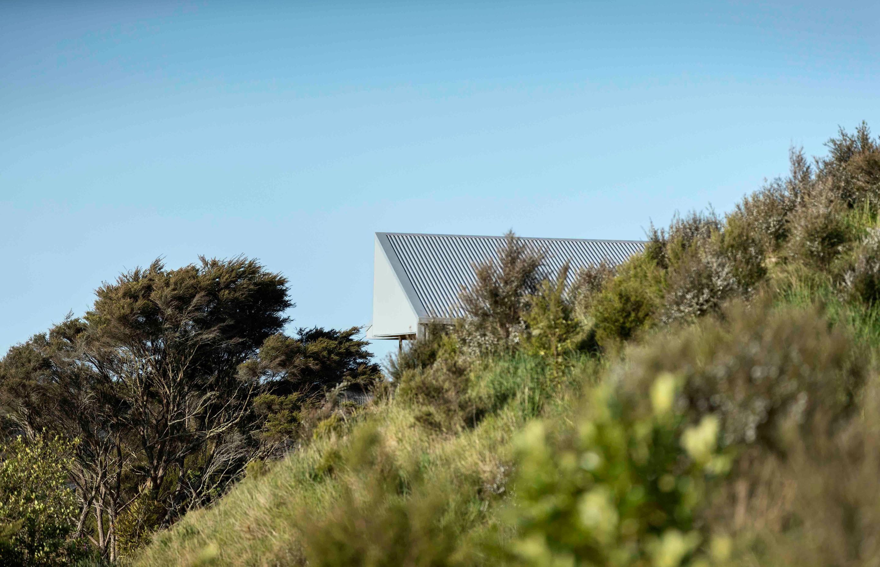 The home crouches just down the slope from the road above.