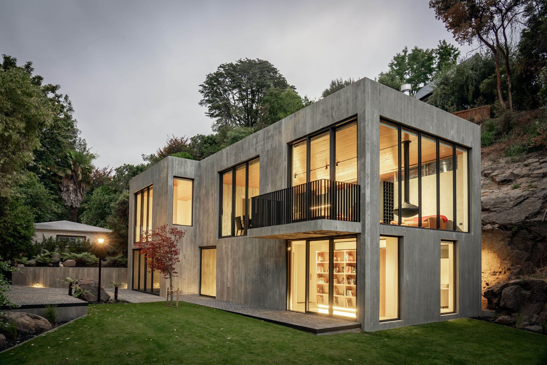 The Brutalist concrete form is punctured by full height glazing on both levels of this two-storyed home.