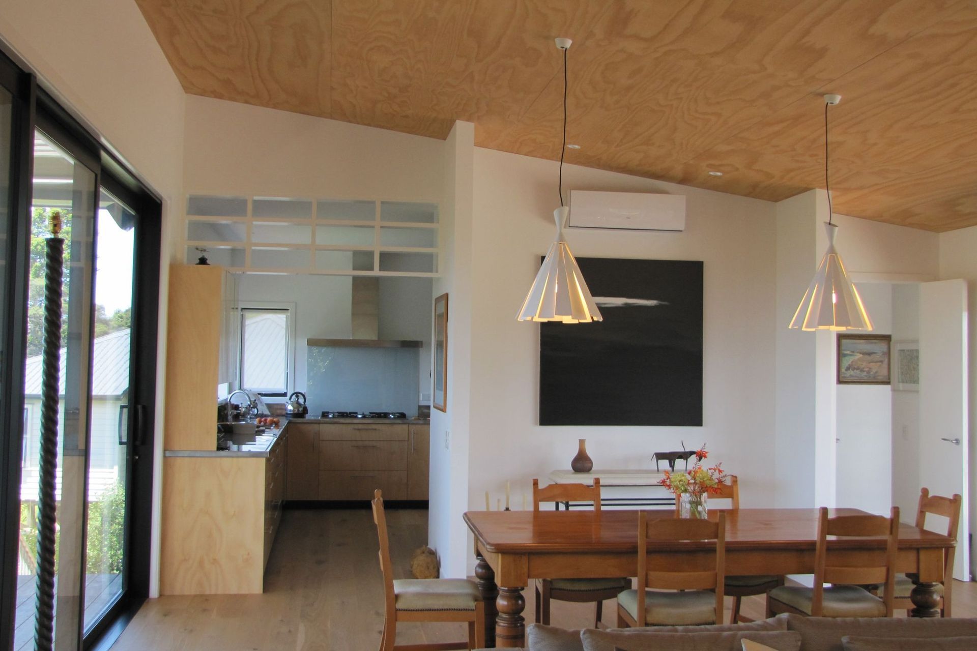Hoop Pine in the kitchen, plywood ceiling sarking and plank flooring provide a light textured finishes against the white walls. The kitchen bench pays homeage to traditional bach stainless steel benches.