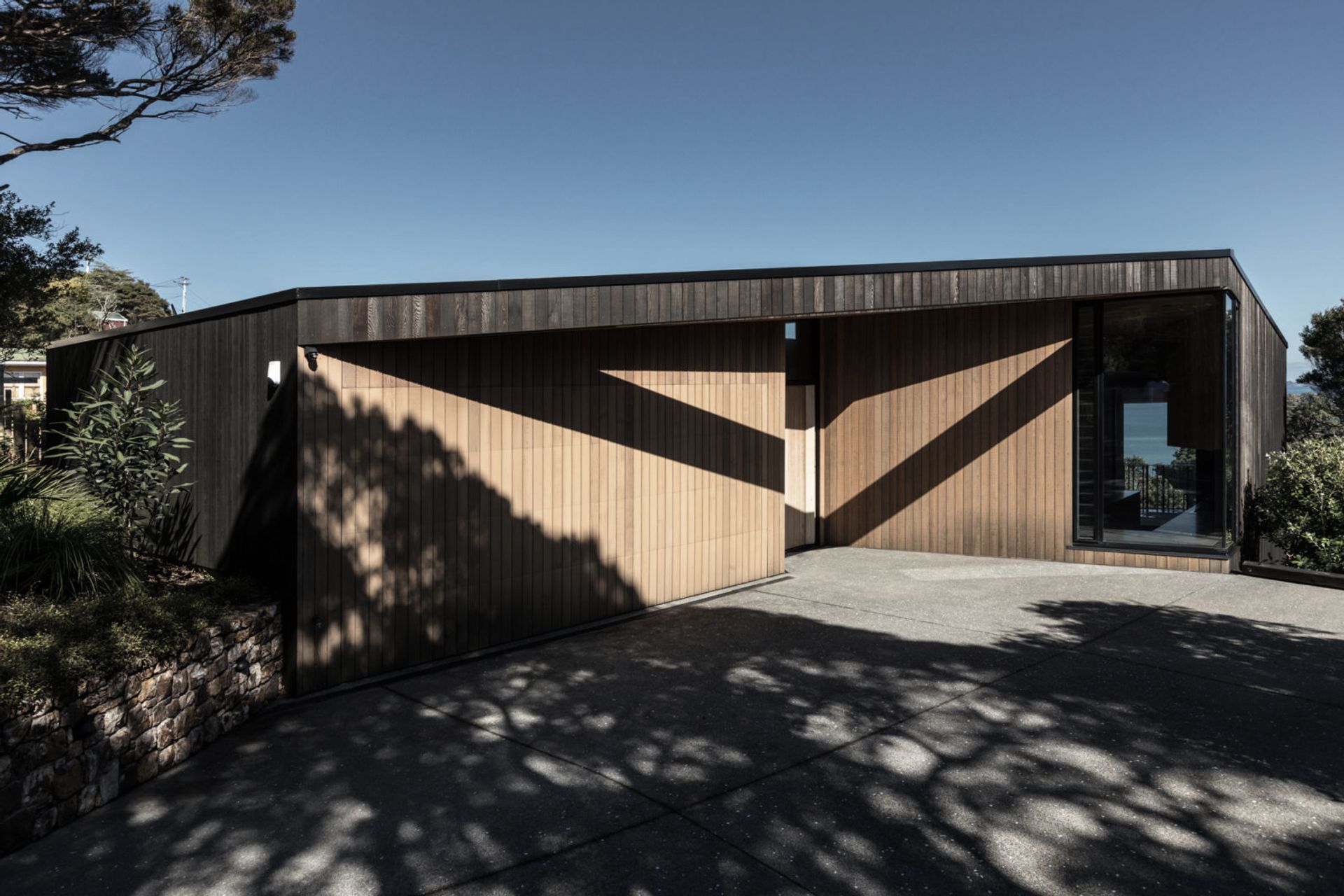 The house reads as a recessive, yet partially exposed, rock-like form.