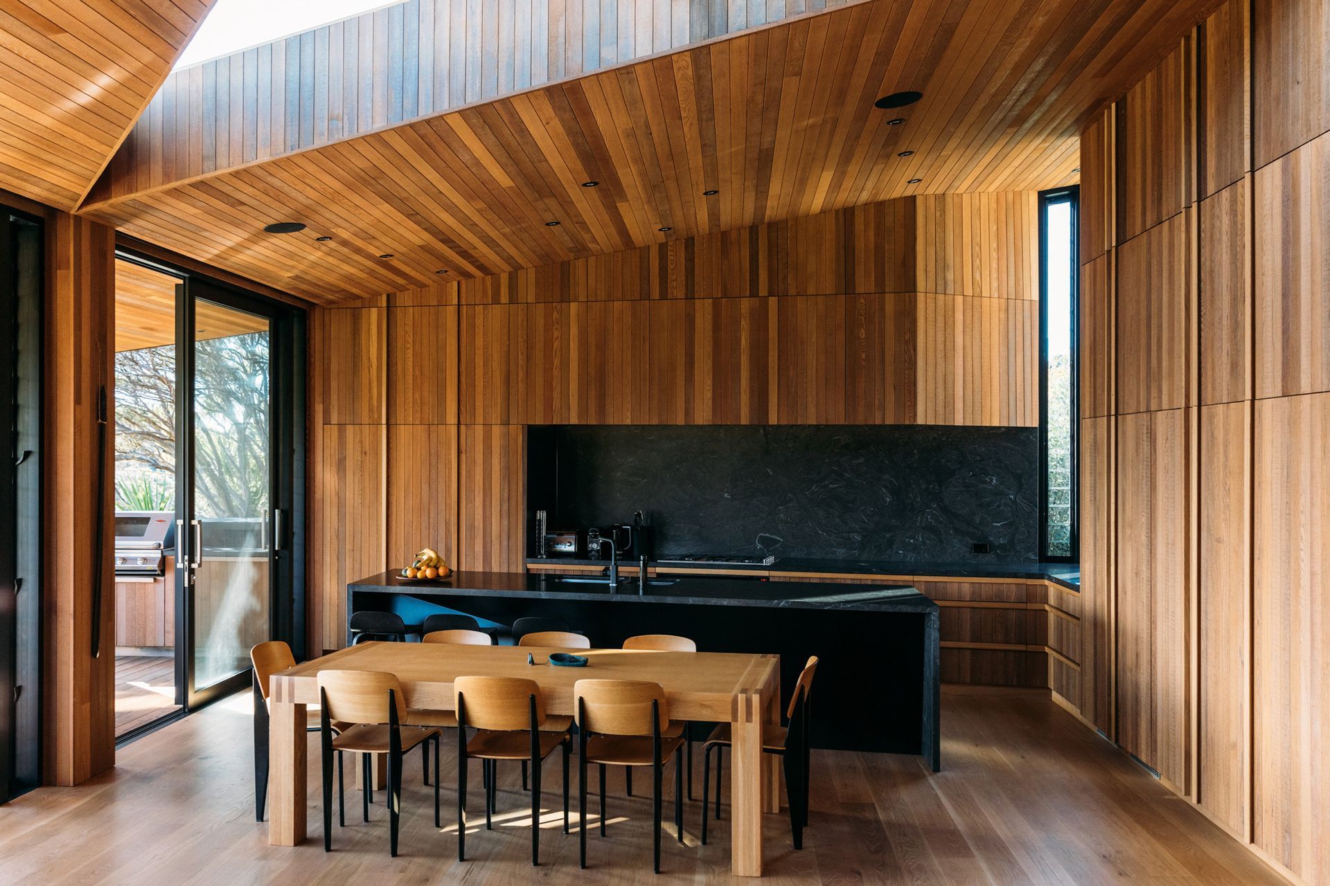 Integrated appliances and cabinetry, coupled with the black of the granite, helps the kitchen recede into the background of the open-plan living area.