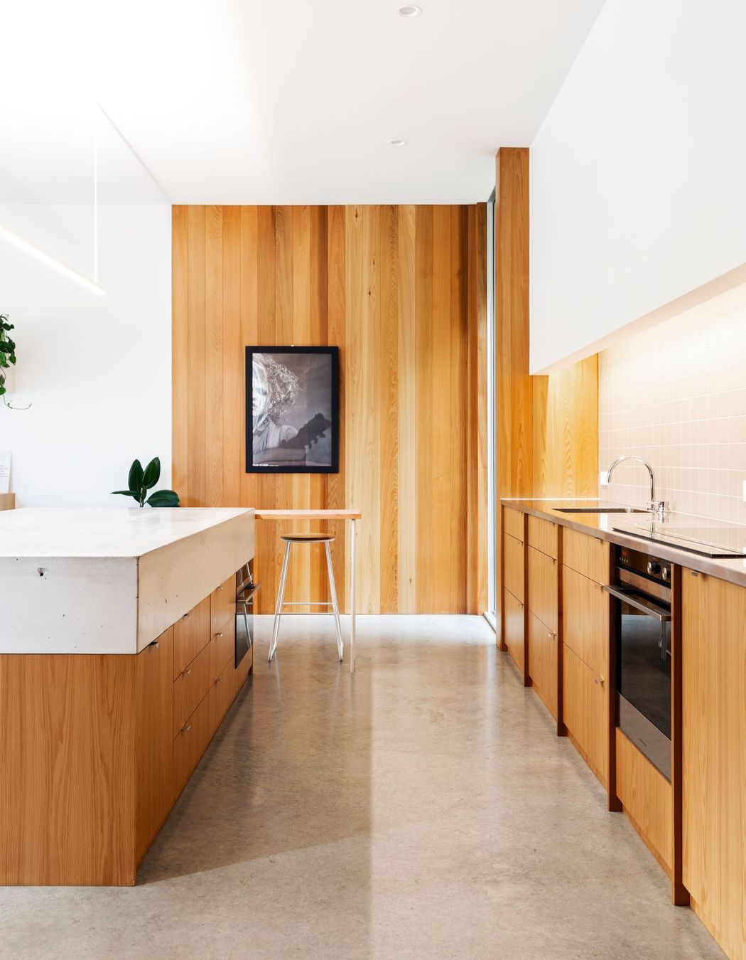 Concrete flooring and timber elements create a restrained palette in the kitchen.