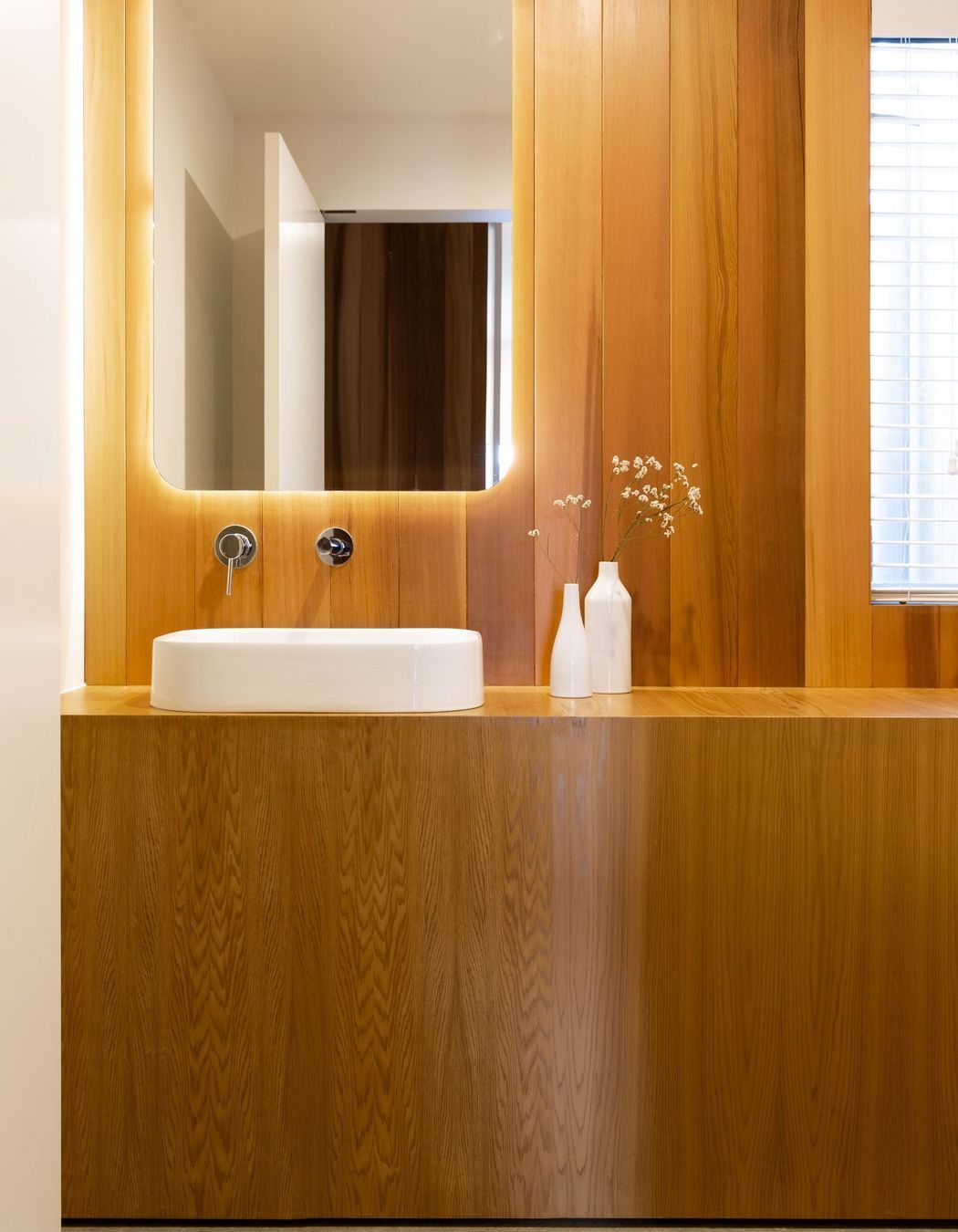 A wall of built-in timber cabinetry and panelling creates a graceful bathroom.