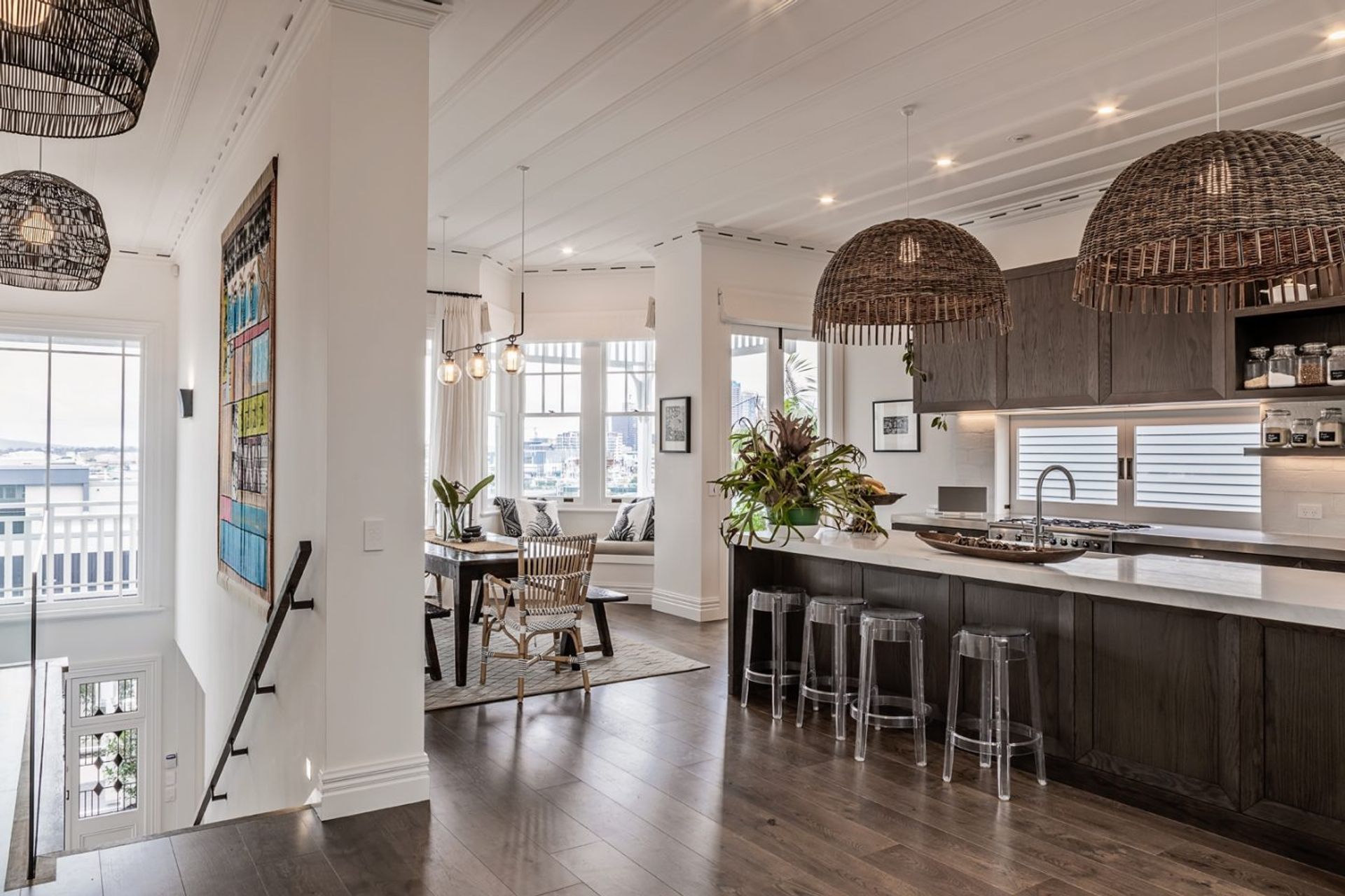 The open-plan kitchen and dining room leads to a bay window overlooking the city. An original board-and-batten ceiling, painted white to match the walls, provides a contrast to the dark oak flooring and cabinetry.