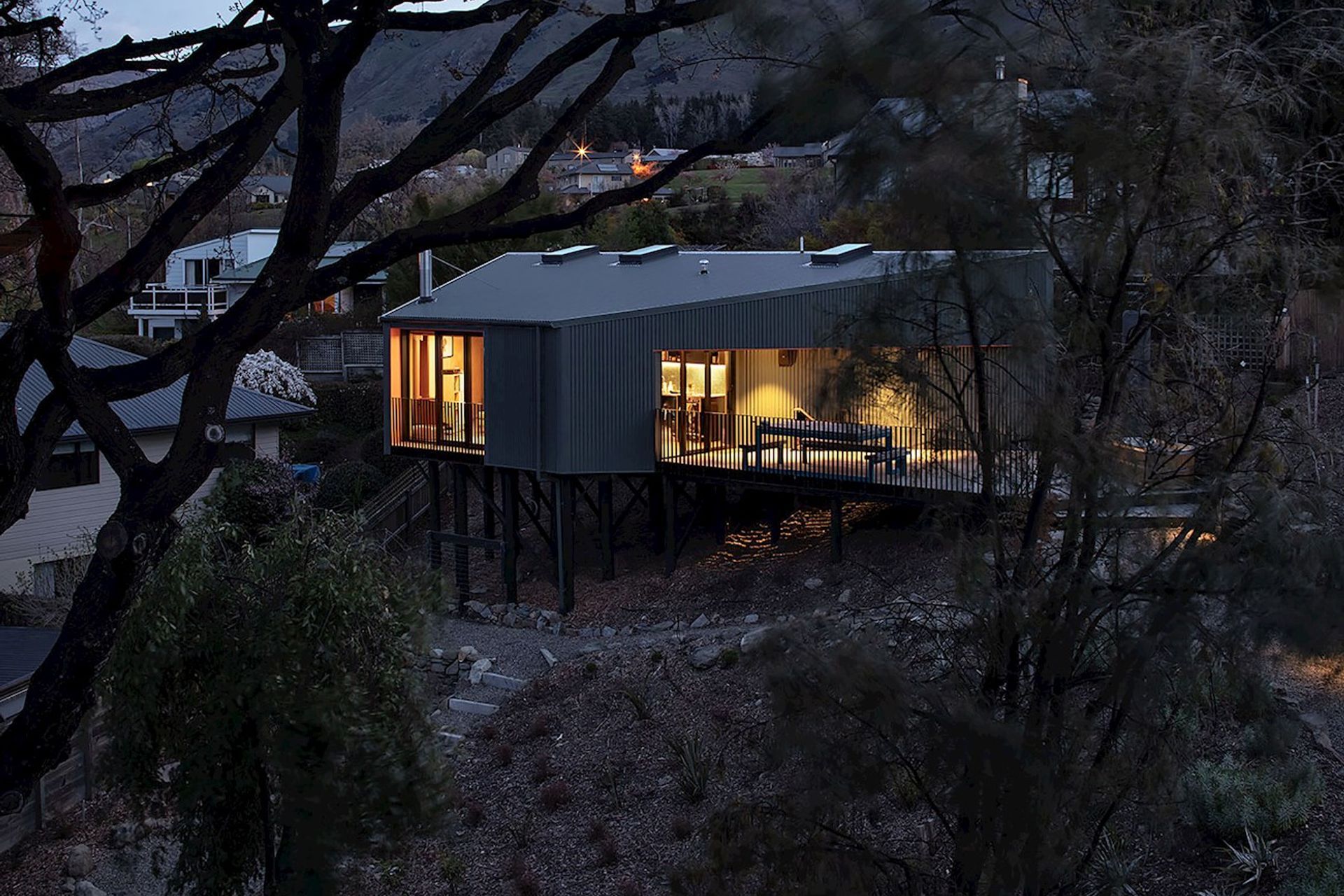 On a very steep site in Wanaka, this modest holiday home is elevated up on poles, like a kea bird perched in the trees.