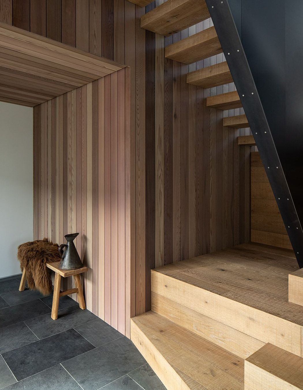 Slate tiles and a steel ballastrade provide a strong contrast to the warm timber on the staircase.