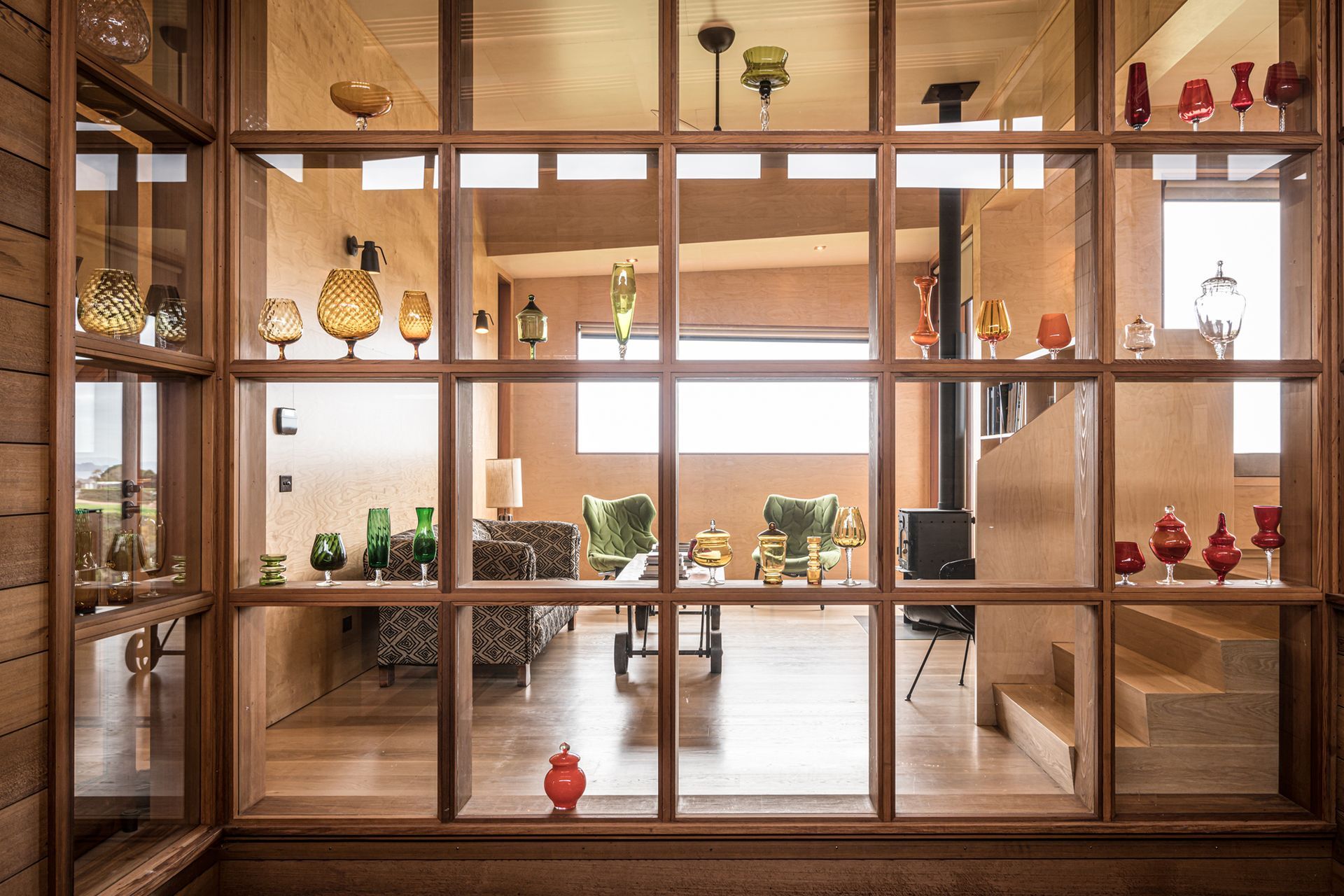 The owners’ glass art collection is showcased in this timber display case that forms the backdrop to both the courtyard and lounge. Photograph by ArchiPro.
