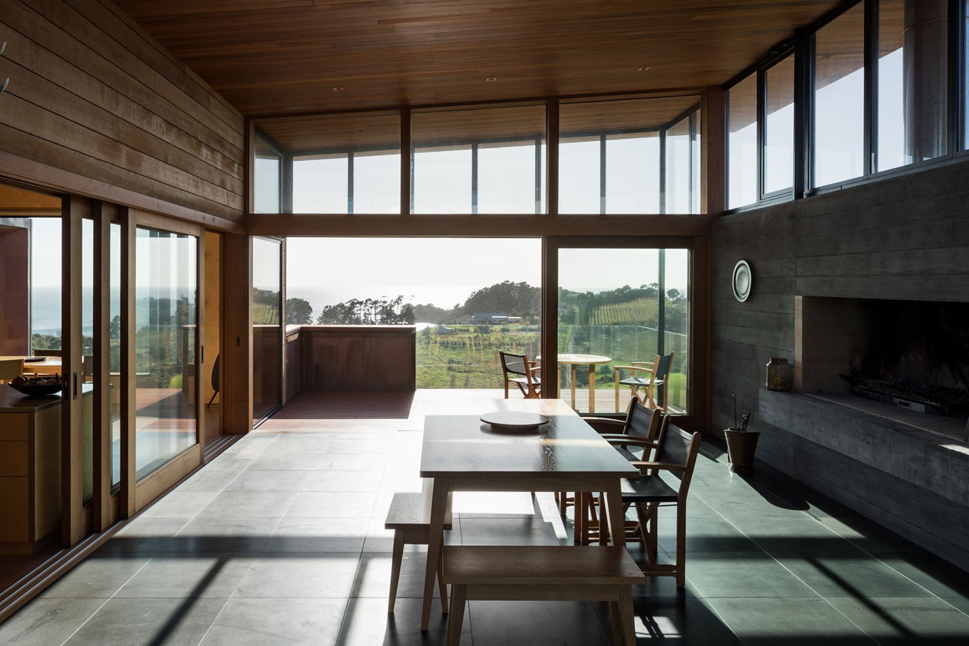 Looking through the entertainment room, across the balcony to expansive views over a vineyard of Syrah grapes, Oneroa Bay to the right and bush to the east.