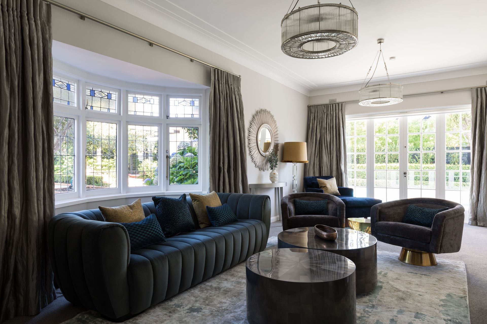 A teal three seater sofa, dual coffee tables and two swivel chairs