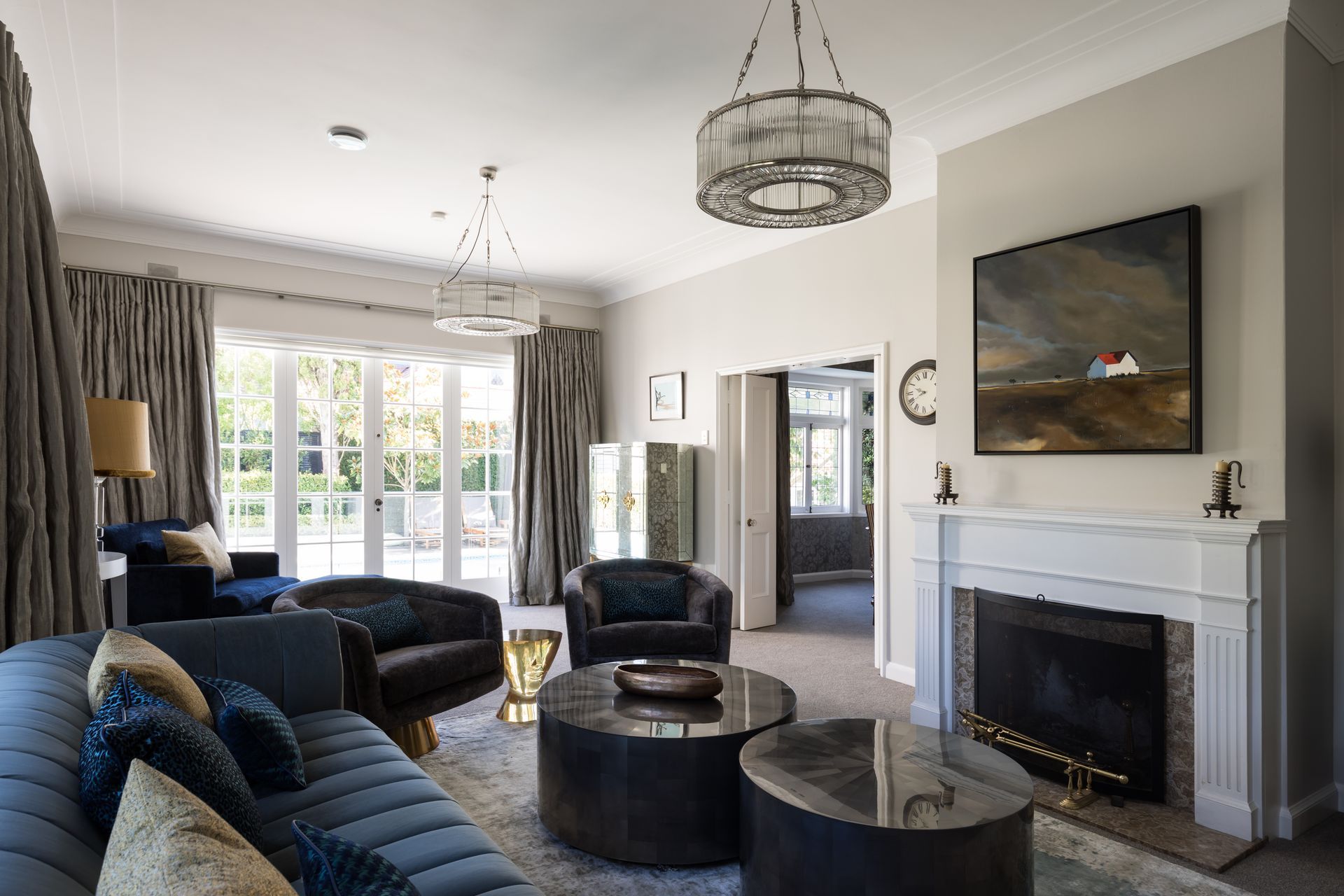 A teal three seater sofa, dual coffee tables and two swivel chairs