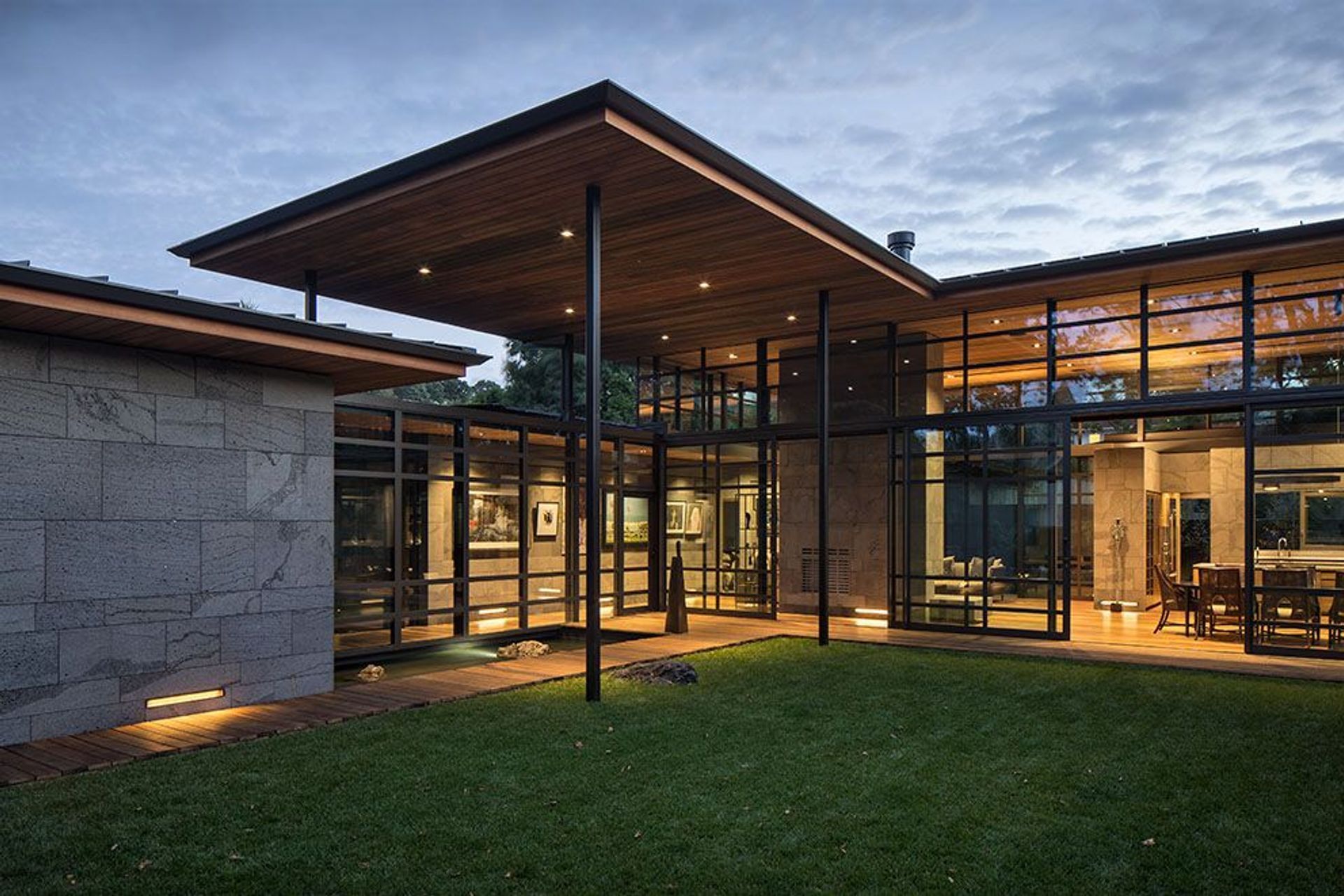 Surrounding the central courtyard (left to right) is the garage and its entry corridor, the main entryway with cantilevered roof overhang and the open-plan living/kitchen/dining space. 