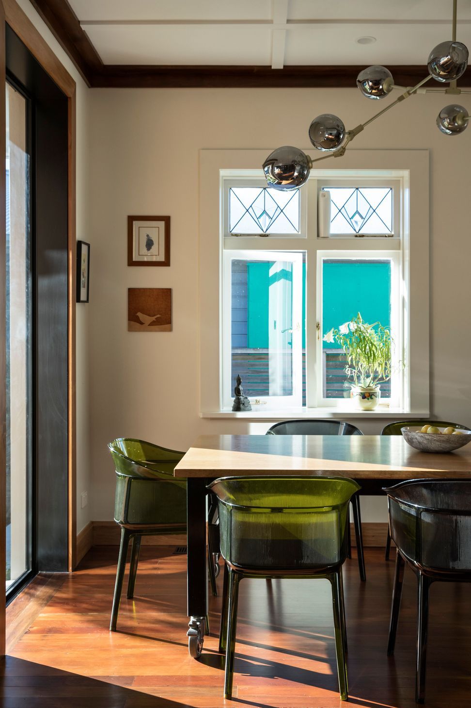 The junction between the original bungalow and the contemporary addition is expressed through carefully detailed materials. Timber flooring, bespoke joinery, Kartell dining chairs and a sculptural pendant light create a refined dining space filled with warmth and natural light.