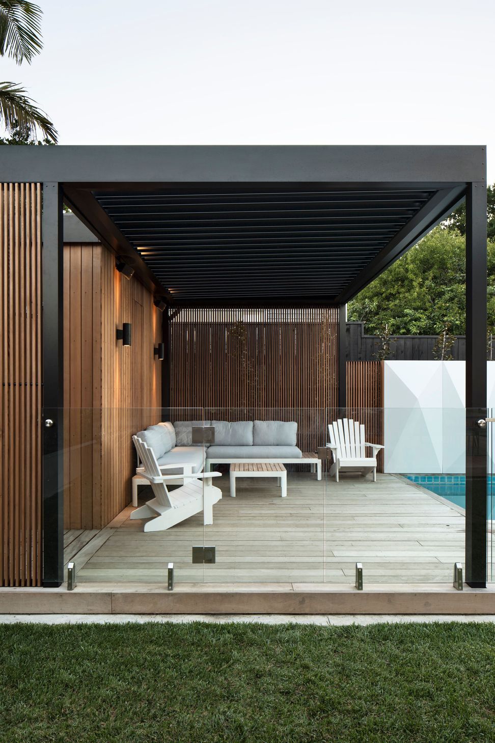 The pool cabana provides a contemporary retreat overlooking the swimming pool. Clad in vertical cedar weatherboards with black Louvretec louvres and surrounded by timber decking, it extends the home's outdoor living spaces while complementing the surrounding landscape.