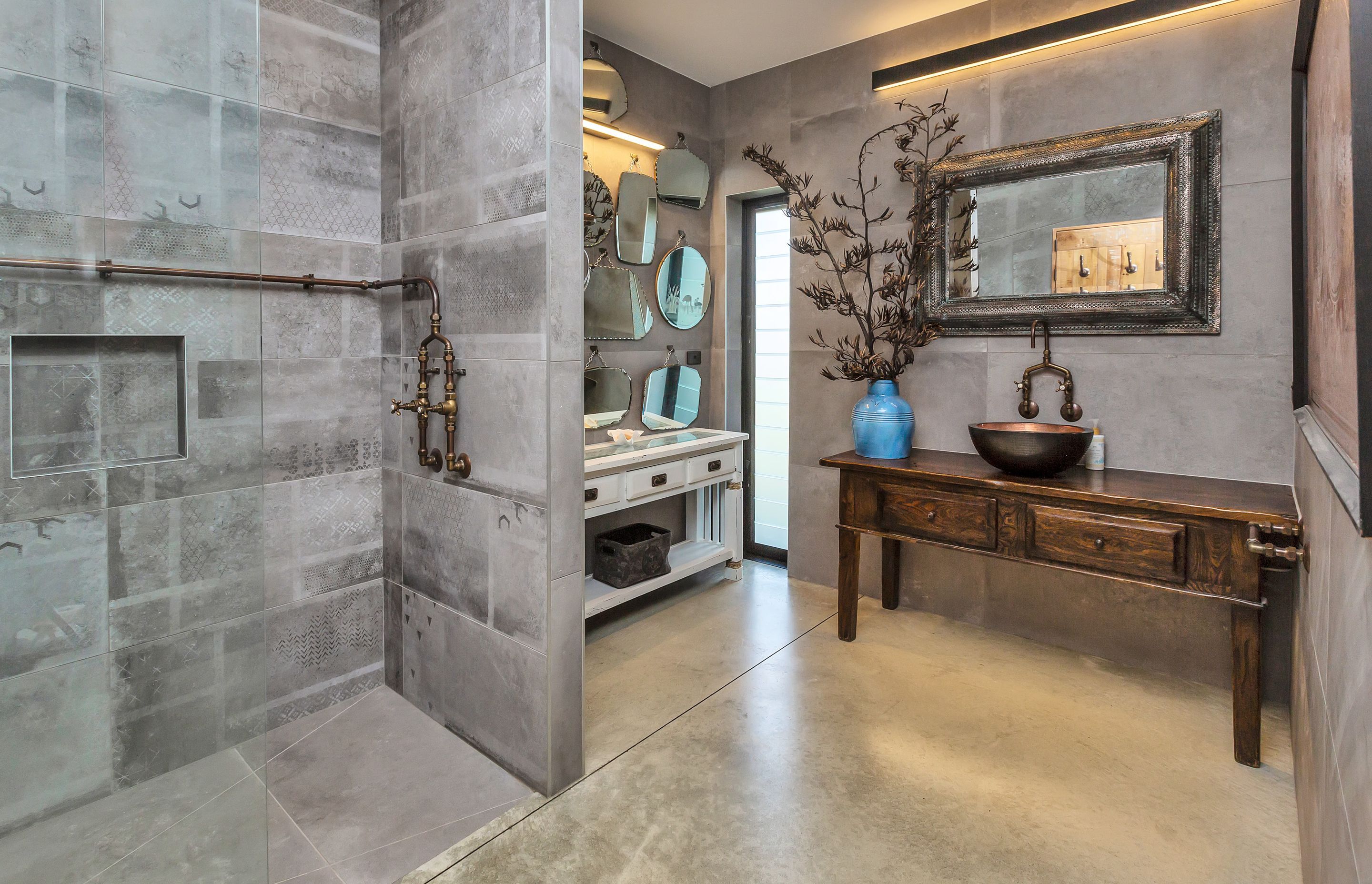 Antique and handcrafted cabinetry and mirrors are a feature n another of the bathrooms, along with recycled copper exposed pipework and tapware.