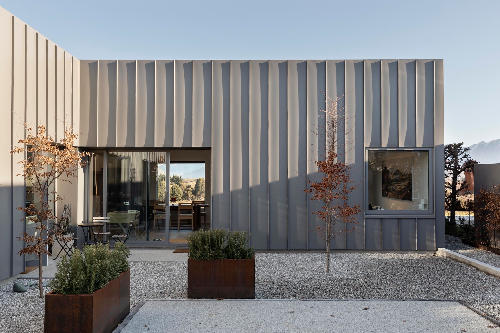 The sheltered extenal courtyard has an almost Mediterranean feel, with pale shingle and copper boxed planters.
