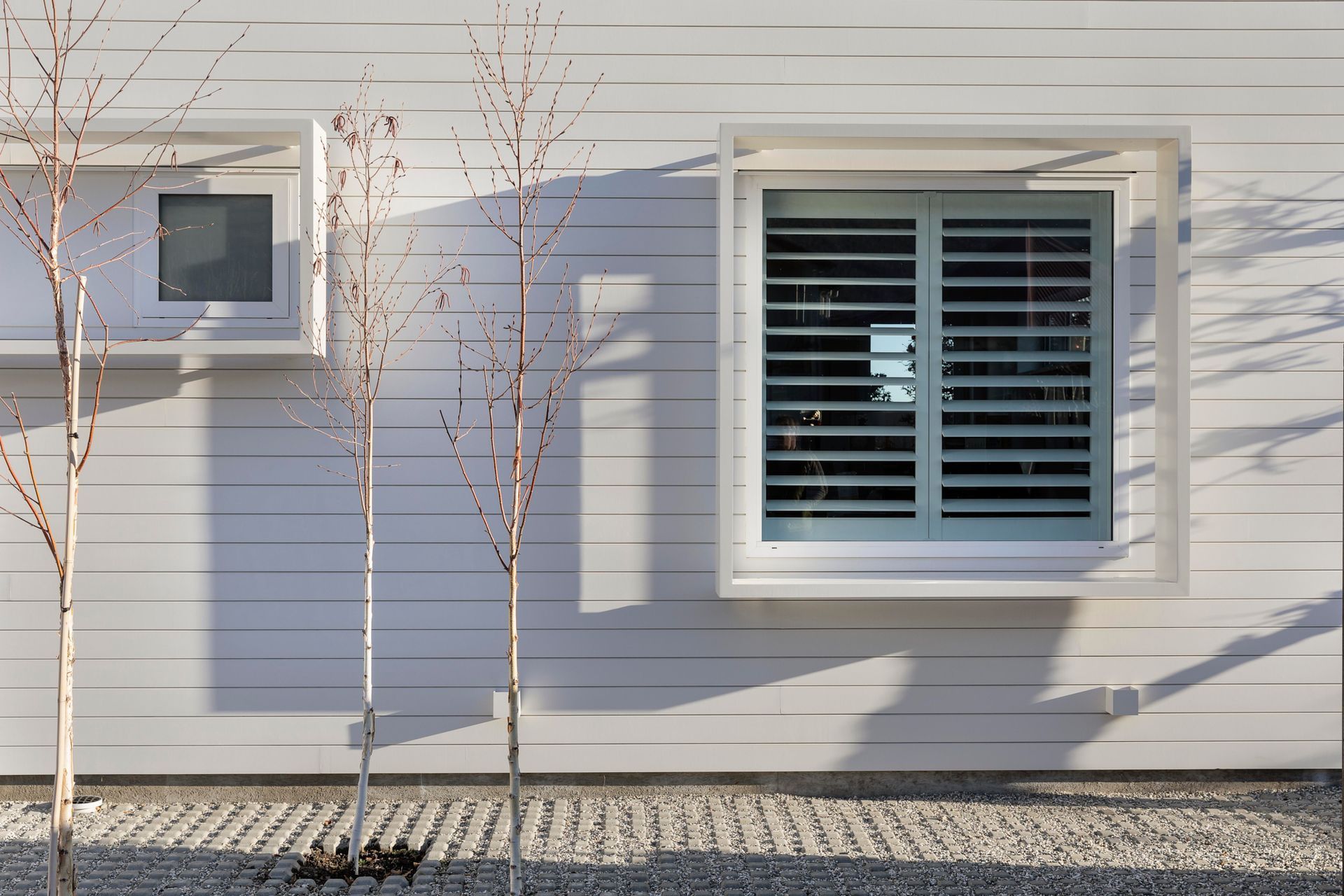 The glazing on the white section of the home is framed with protruding box frames that almost look as if they are floating.