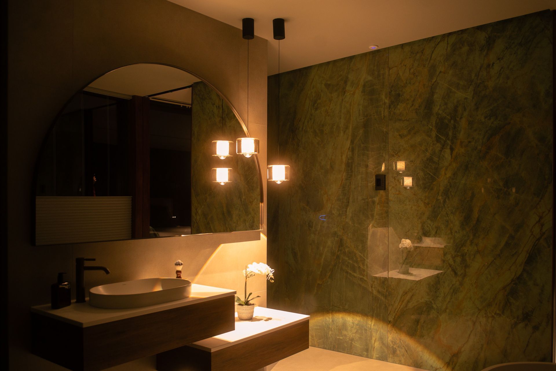 A carefully considered pendant cluster creates a soft, atmospheric glow, casting beautiful shadows across the space while allowing the natural texture and richness of the tiles to shine.