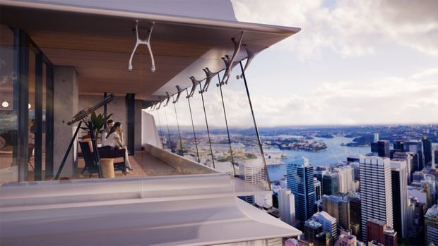 A high-rise rooftop or elevated terrace with a cantilevered timber-lined soffit, extensive frameless glazing, and a dramatic panoramic view over a dense waterfront city. Sculptural suspended swing-like elements hang along the terrace edge, while a small seating and planting area sits beside the interior glazing. The image has a polished contemporary architectural visualization aesthetic.
