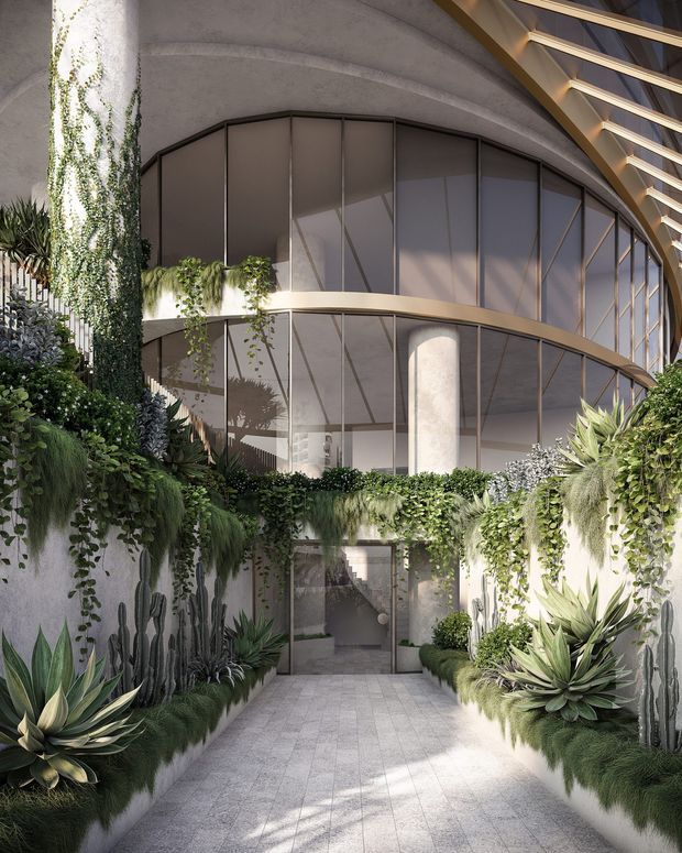 A lush landscaped architectural courtyard or entry passage beneath a sweeping curved concrete structure. The space features extensive vertical and cascading greenery, sculptural succulents and cacti in raised planting beds, pale stone or concrete paving, curved full-height glazing with dark metal frames, cylindrical concrete columns, and a dramatic exposed timber or metal roof structure overhead. The image has a polished contemporary, biophilic character with strong natural light.