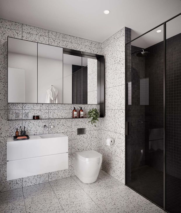 Contemporary bathroom with terrazzo-look speckled wall and floor tiles, a floating white vanity with integrated basin, mirrored wall cabinet, wall-mounted toilet, and a black-framed glass shower enclosure with dark tiled walls. Minimal black and white palette with small natural greenery accents.