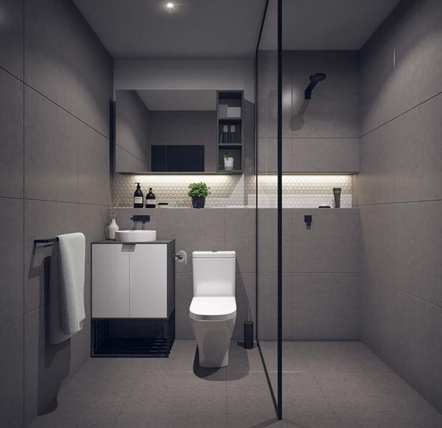 Compact contemporary bathroom with a walk-in glass shower, wall-hung vanity, toilet, large grey wall and floor tiles, and integrated storage. A softly illuminated textured tile backsplash and recessed shelving provide subtle contrast, while black fixtures and framing add definition.