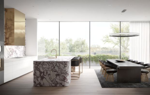 A bright, open-plan contemporary kitchen and dining space with a sculptural veined stone island, white handleless cabinetry, dark timber or wood-look flooring, and a large dark dining table. Full-height glazing looks onto a planted outdoor area, while a slim circular pendant hangs above the dining table. The palette is restrained in white, grey, black, and warm timber tones.