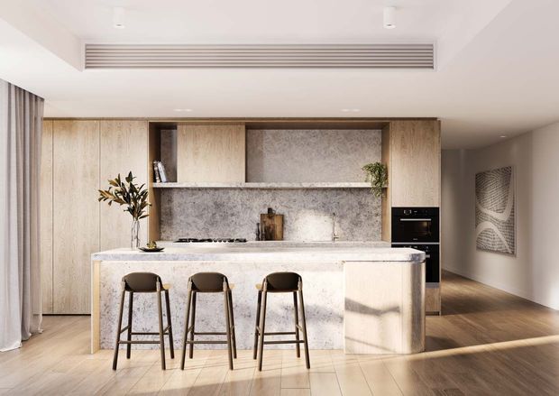 A bright, refined contemporary kitchen with a large stone island and three bar stools, full-height light timber cabinetry, open shelving, integrated appliances, and a textured stone backsplash. The kitchen opens toward a timber-floored living or circulation area, with soft curtains and minimal decor.