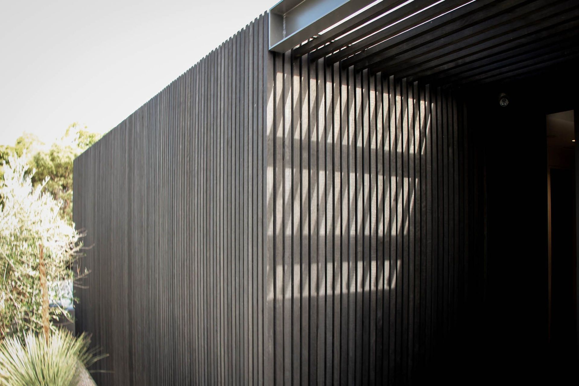 The Dual House - Exterior. Charred vertical battens casting shadow lines across the facade.