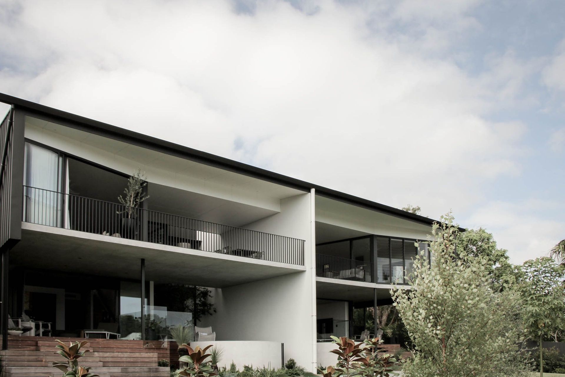 The Dual House - Exterior. Two storey rear elevation with deep balconies and a curved concrete planter.