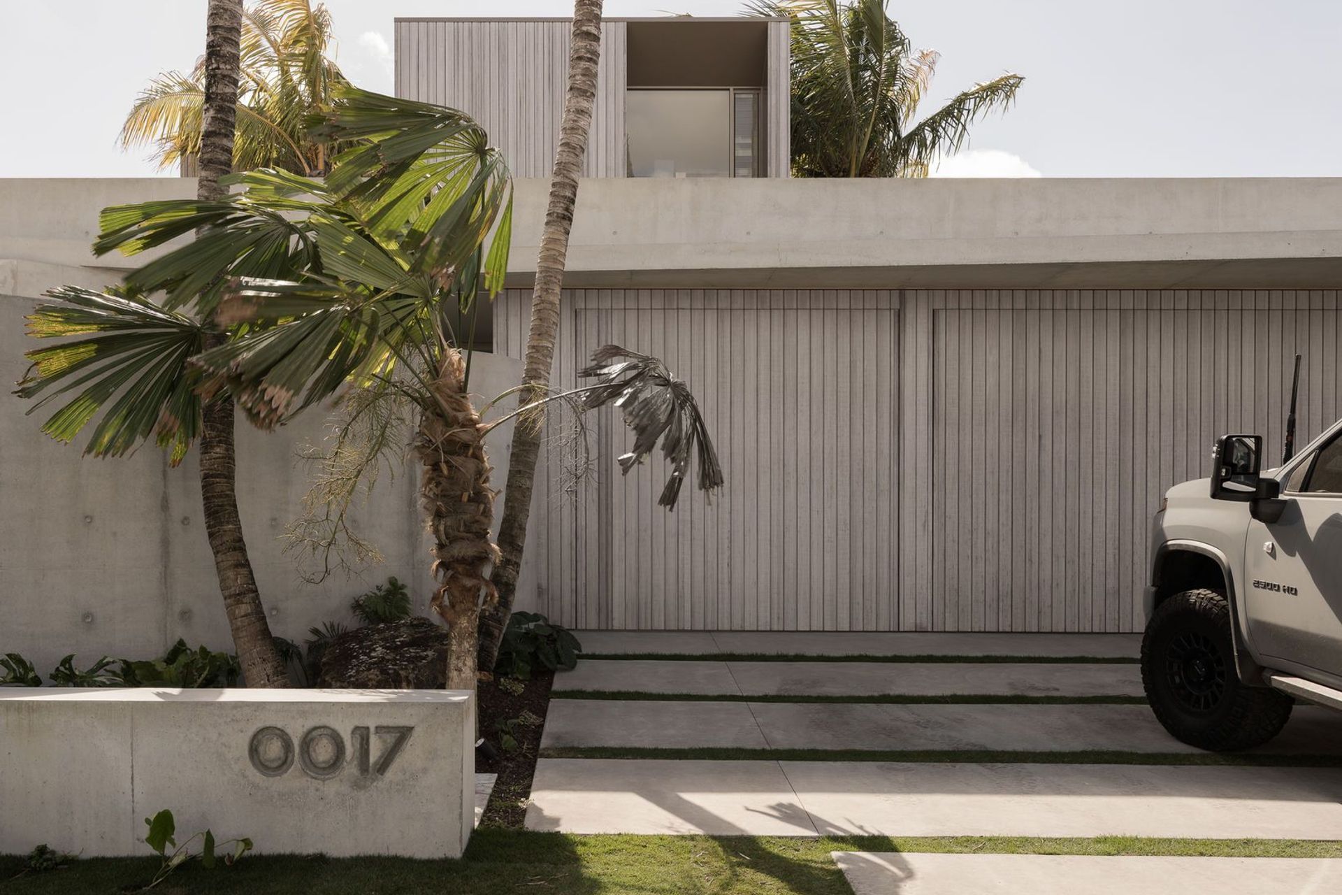 Solmere - Exterior. Concrete planter and house number set among palms at the front entry.