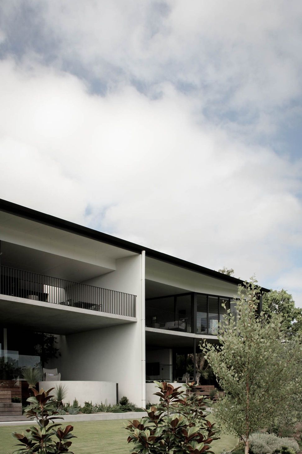 The Dual House - Exterior. Deep roof overhang and balcony framing the sky.