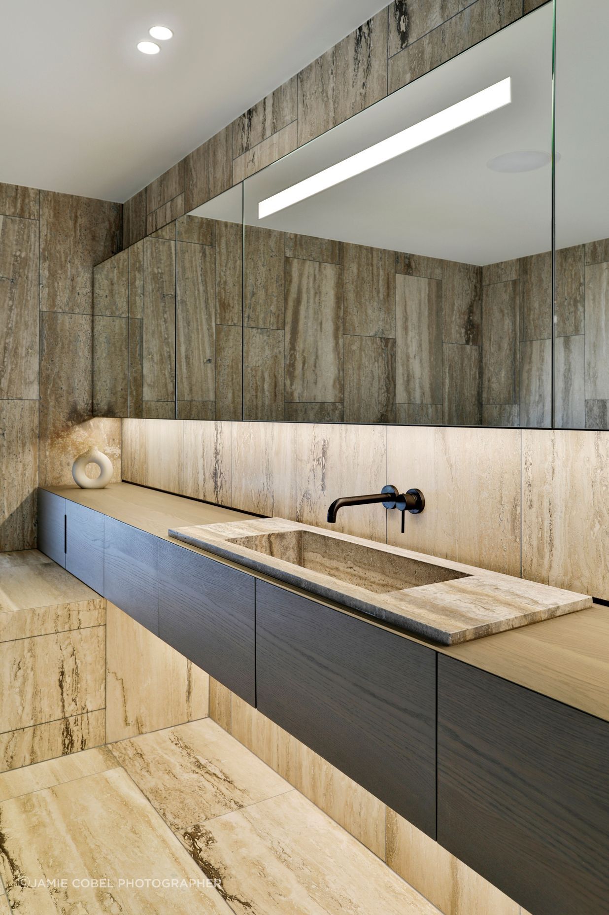 A bathroom continues the travertine materiality.