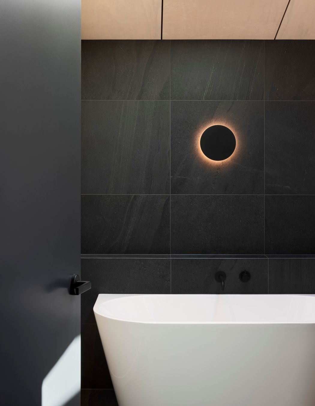 Natural timbers give way to dark stone tiles in the bathroom for a modern twist on the classic 'black and white' look.