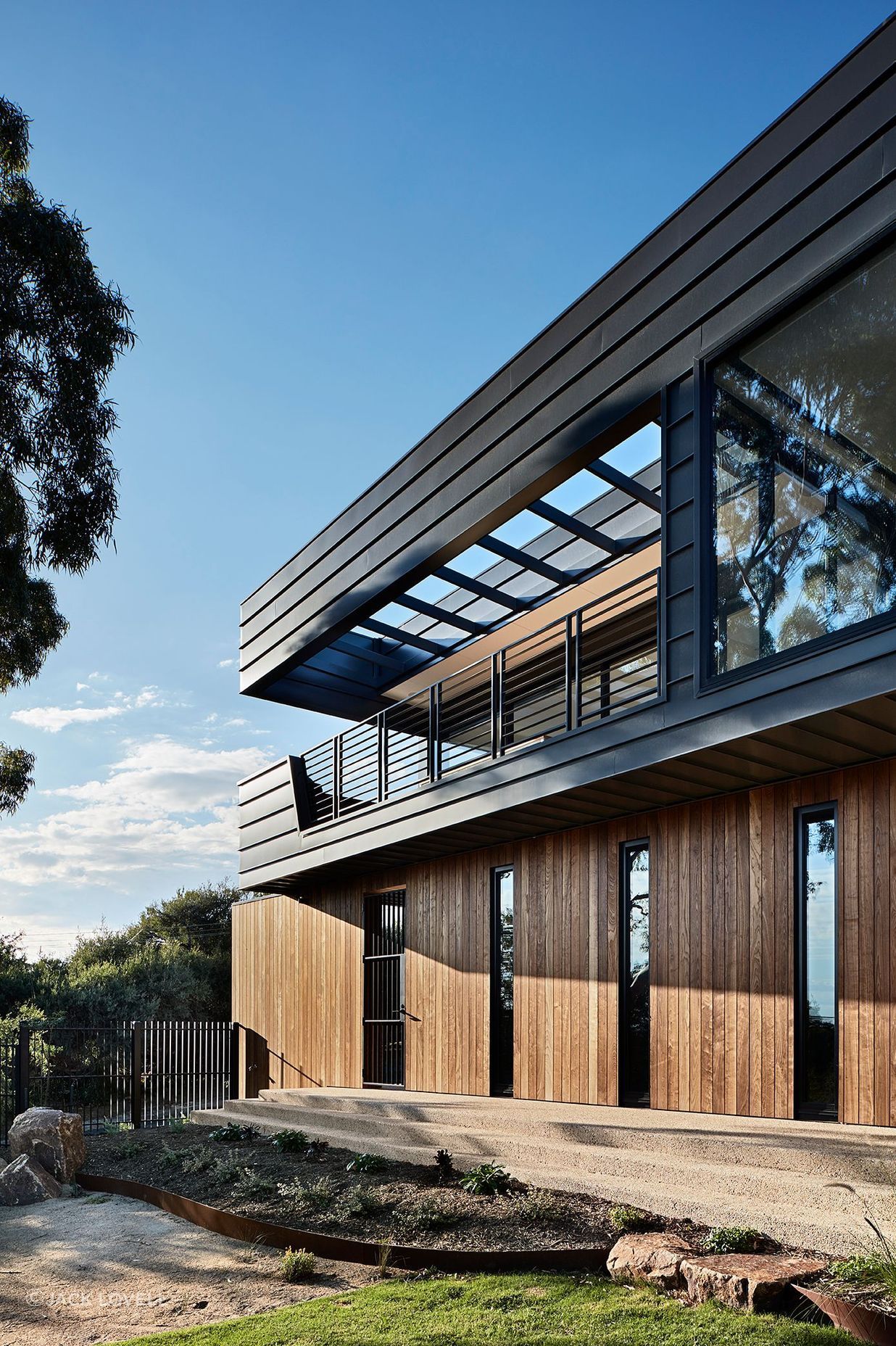 The solid timber cladding of the lower floor provides a base for the open air balcony above.
