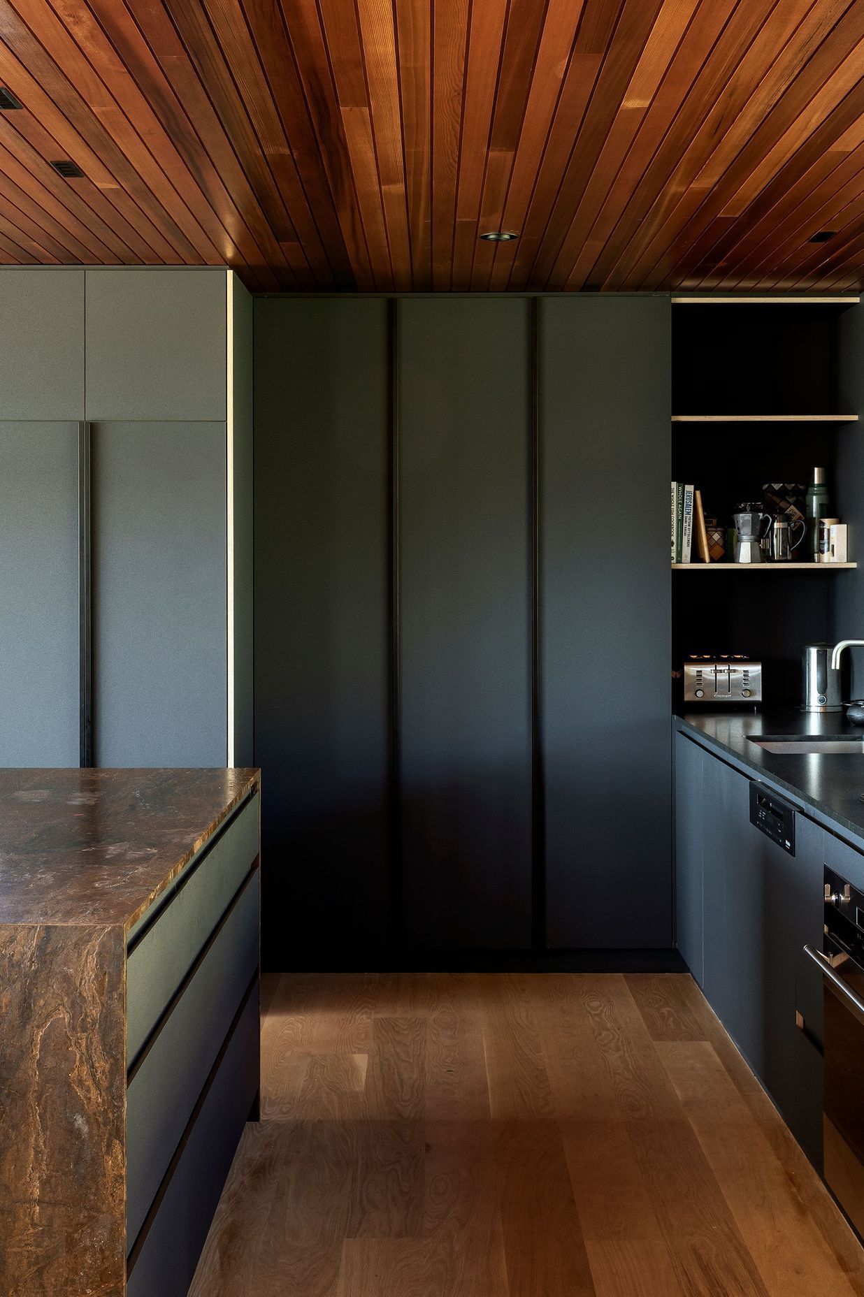 The bronzite benchtop and dark cabinetry give the kitchen a recessed and moody feel.