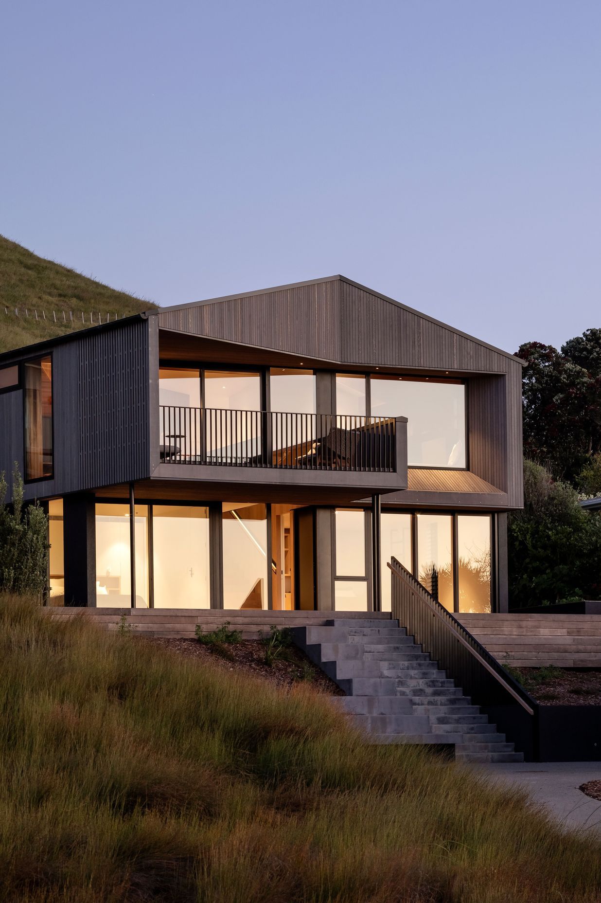 The dart shape of this Otama Beach holiday home recesses its form neatly into the hillside.