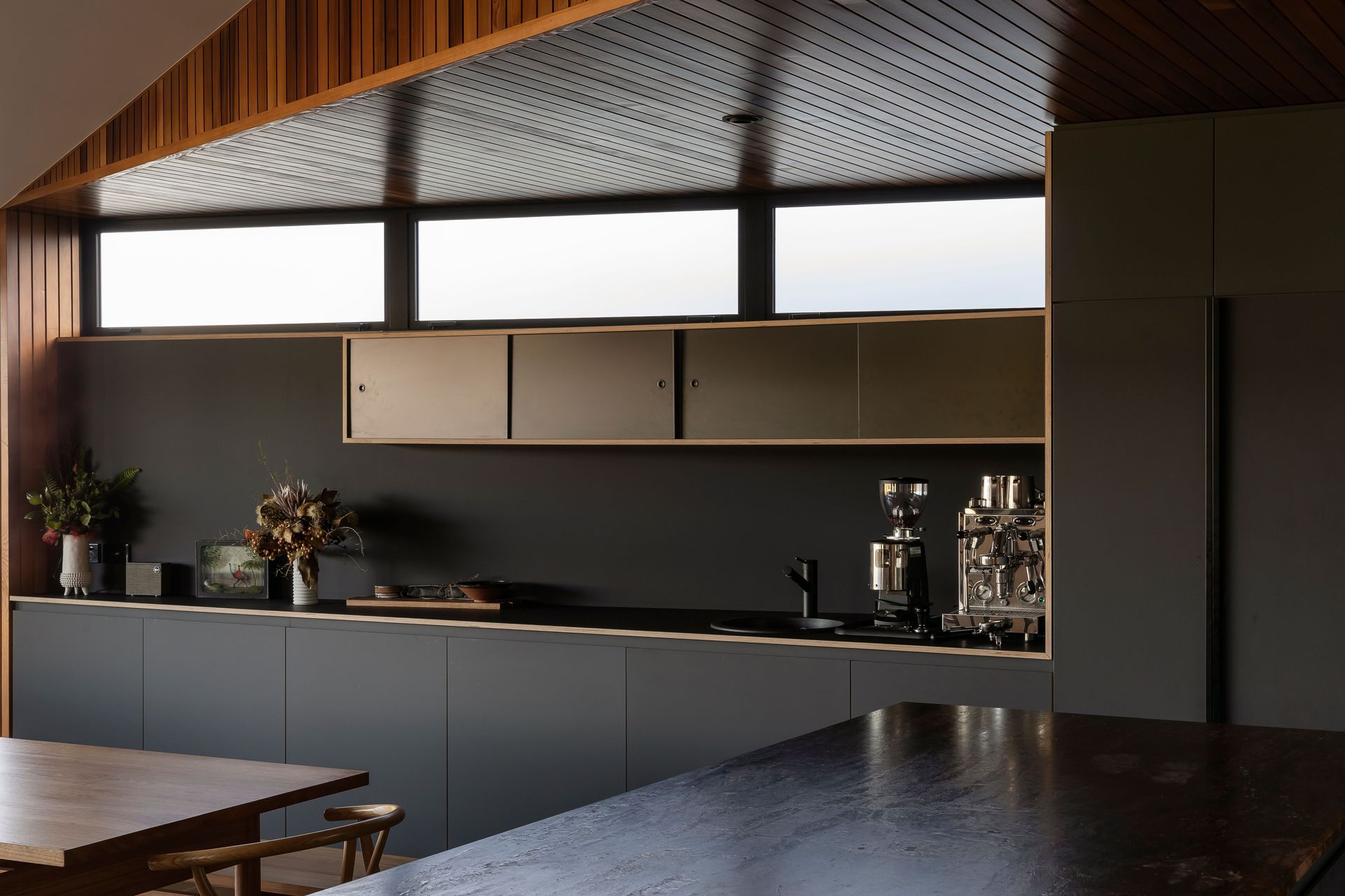 The dark kitchen cabinetry juxtaposes the warm and light interior.