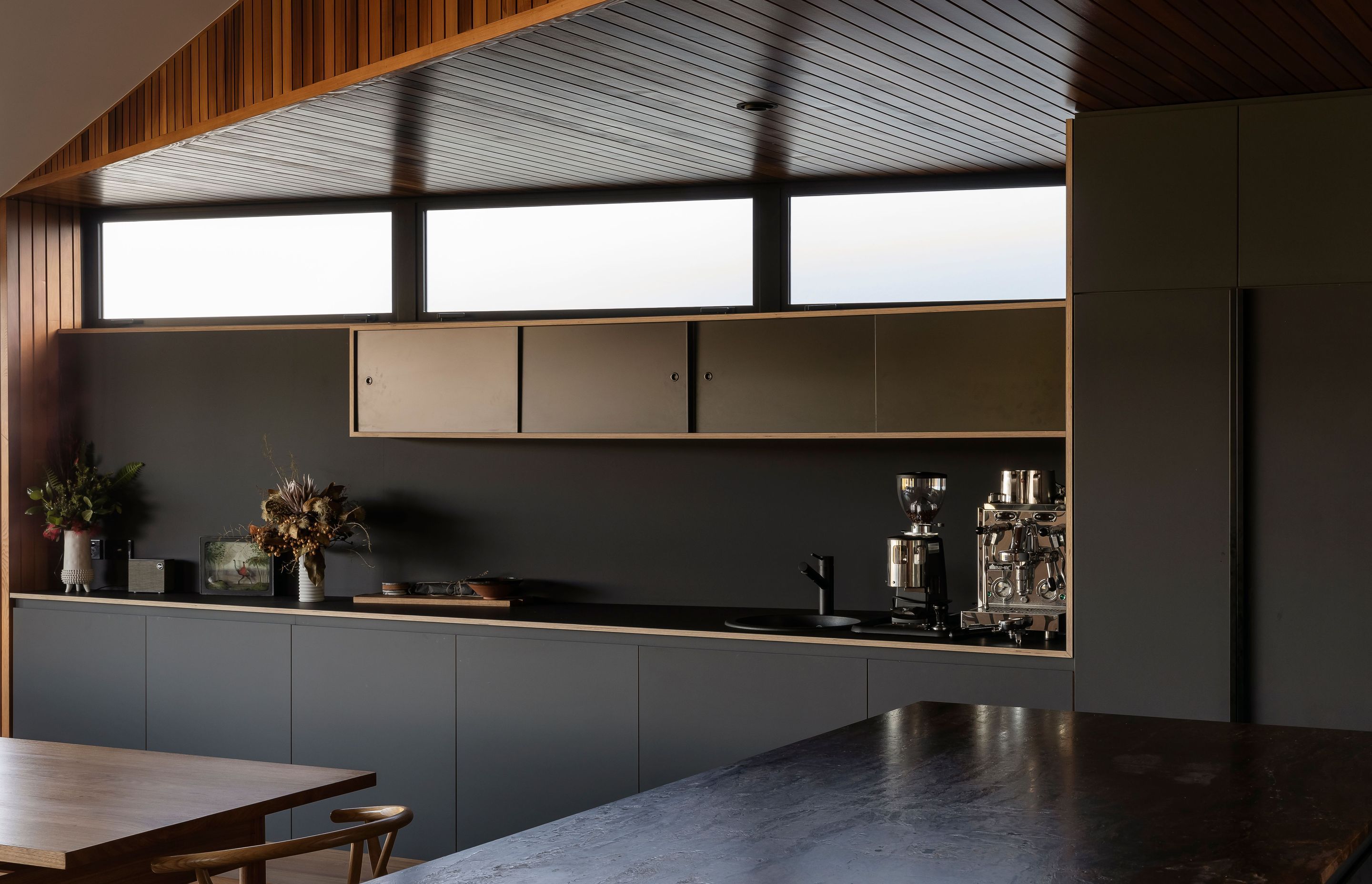 The dark kitchen cabinetry juxtaposes the warm and light interior.