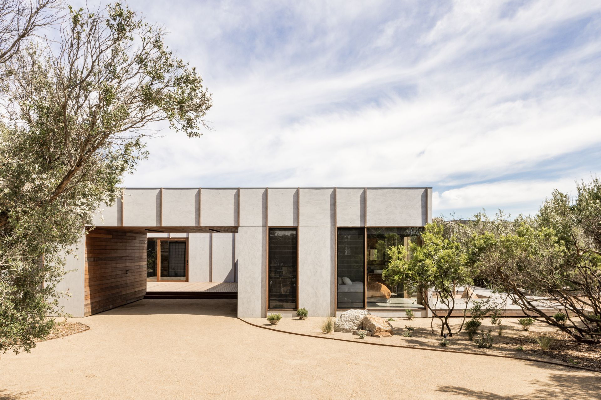 A rhythmic pattern of vertical timber battens over smooth cement cladding defines the front facade of Tea Tree House