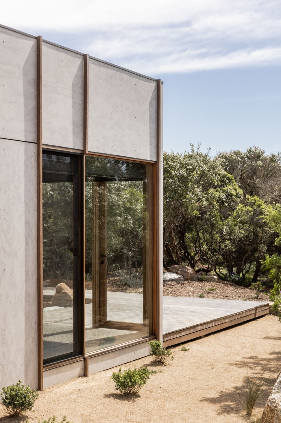 Large floor-to-ceiling windows punctuate solid walls to provide expansive coastal tea tree views