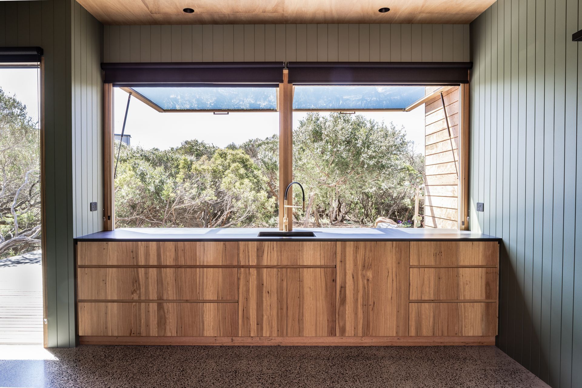 large awning windows open up the kitchen wall to create a cafe - style servery for seamless indoor - outdoor dining