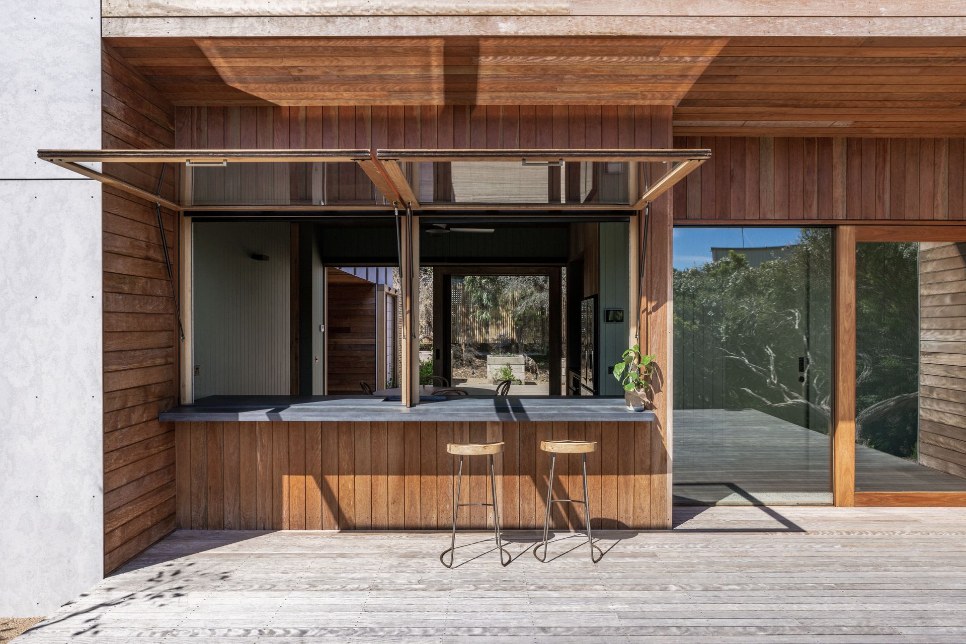 large awning windows open up the kitchen wall to create a cafe - style servery for seamless indoor - outdoor dining