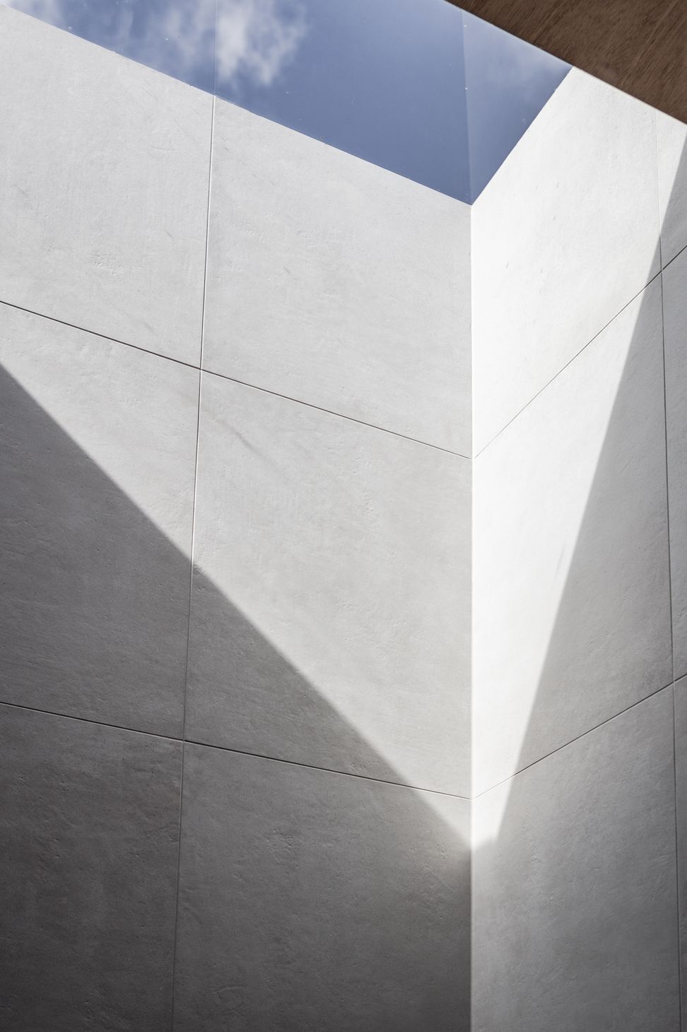 Frameless skylight illuminating the walk-in shower's silver-grey tiled walls