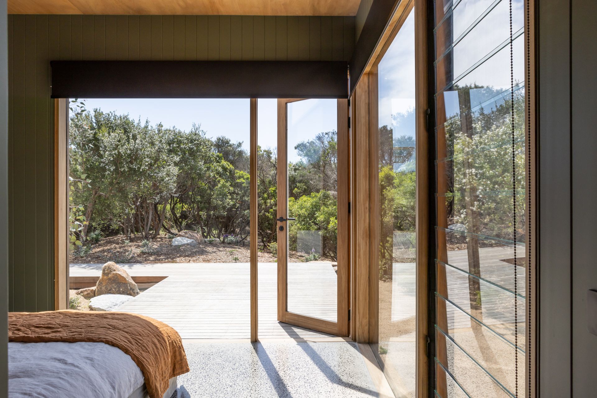 Floor to ceiling timber framed windows open up the master bedroom revealing the coastal garden landscape