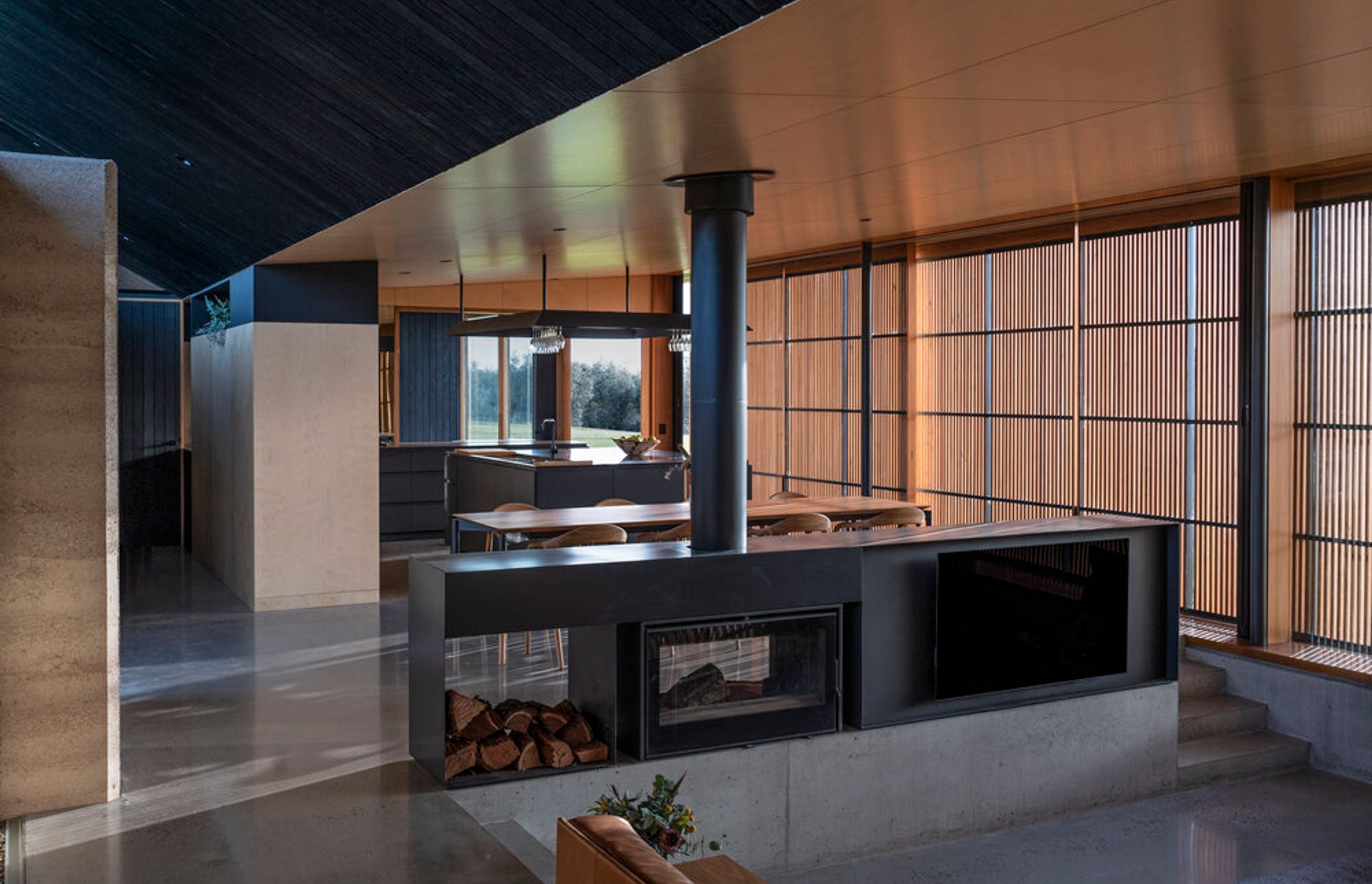 Unwind in style by the crackling fire: The mesmerizing Axis i1000 Freestanding Double Sided fireplace at Mystery Bay House creates a cozy sanctuary within the modern architectural marvel
