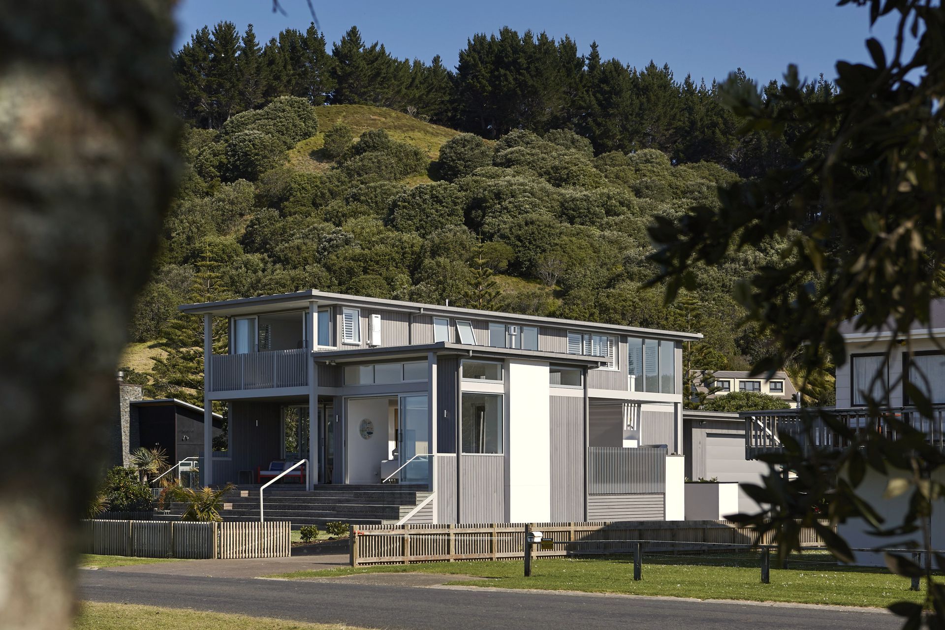 Viewed from the surrounding landscape, Driftwood sits comfortably within the rolling hills and native bush of the Coromandel. The restrained material palette allows the contemporary beach house to blend naturally into its spectacular coastal environment.