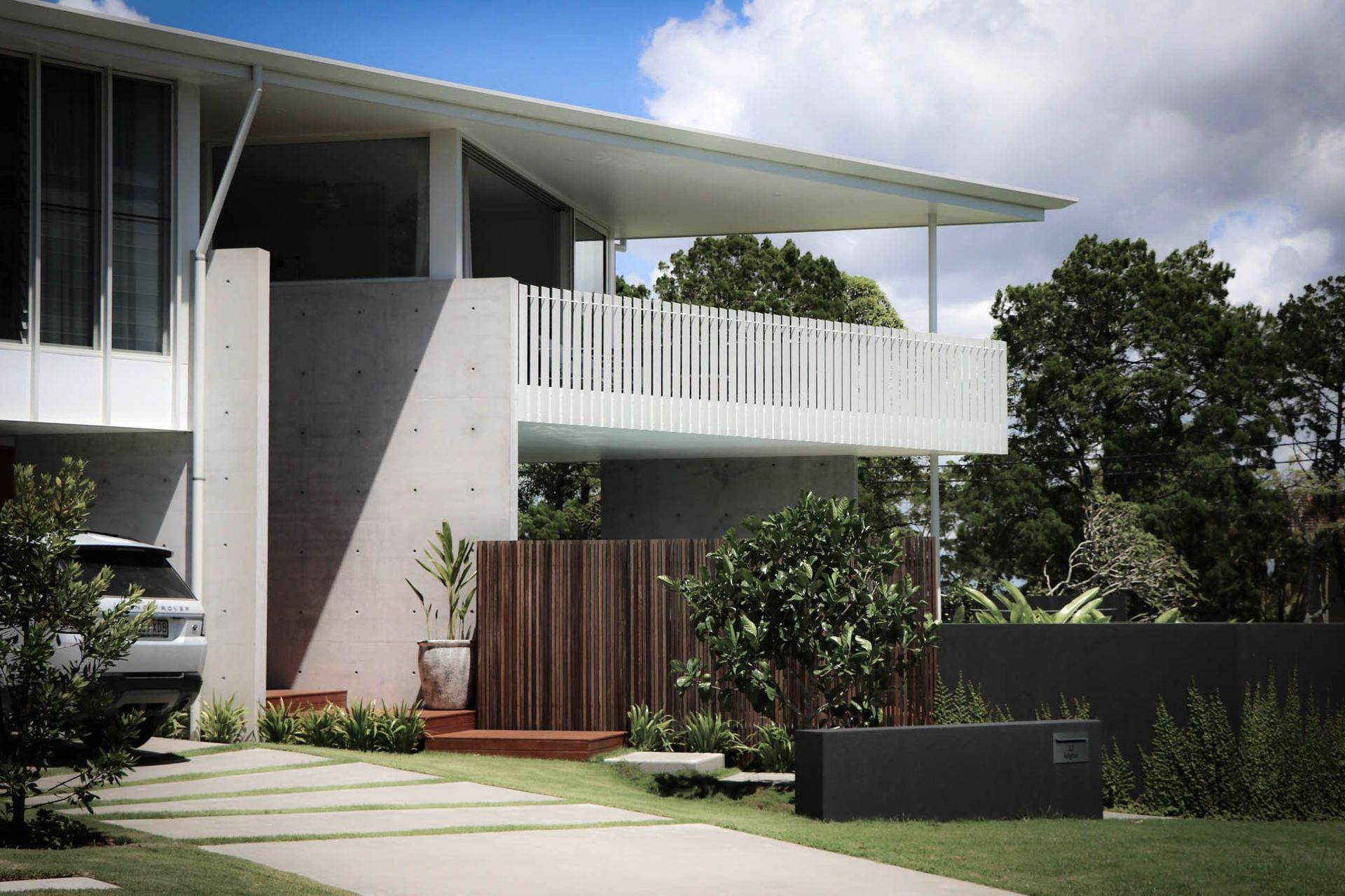 Shipp Residence - Exterior. Two storey facade with a white battened balcony and concrete walls.